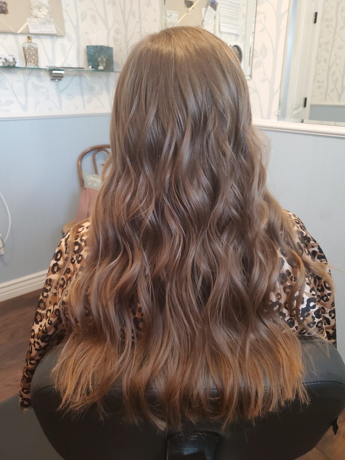 Long bronde hair with a soft blonde balayage and loose waves, shown from behind.