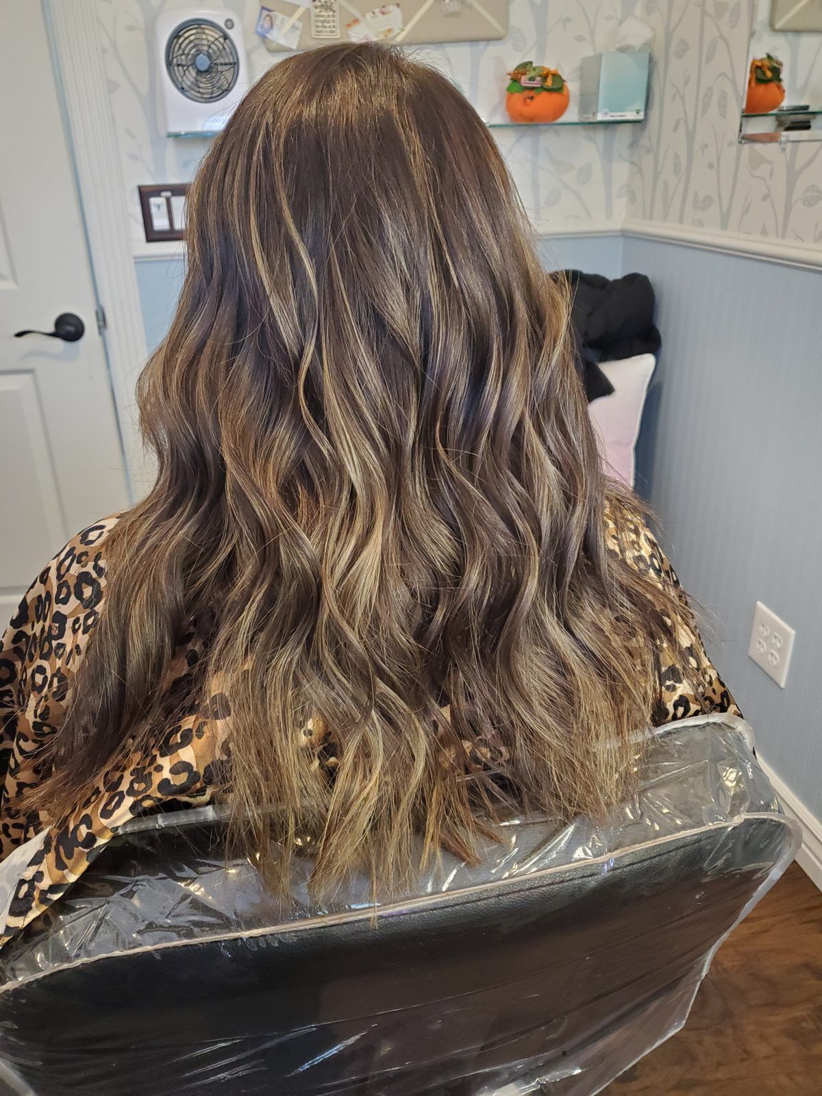 Brunette hair with soft blonde balayage ribbons and loose waves, shown from behind.