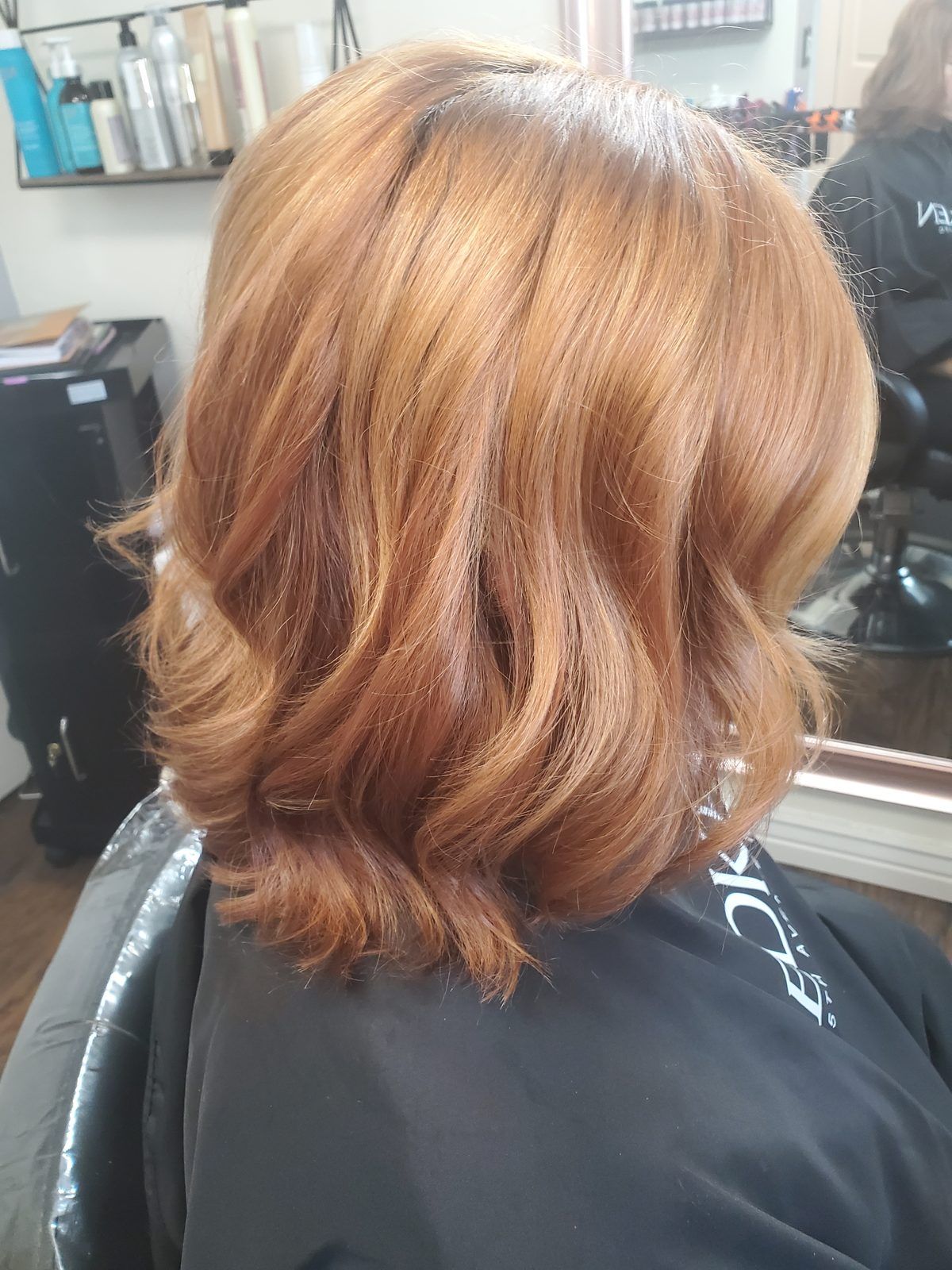 Warm copper and strawberry-blonde bob with soft waves, shown from the side.