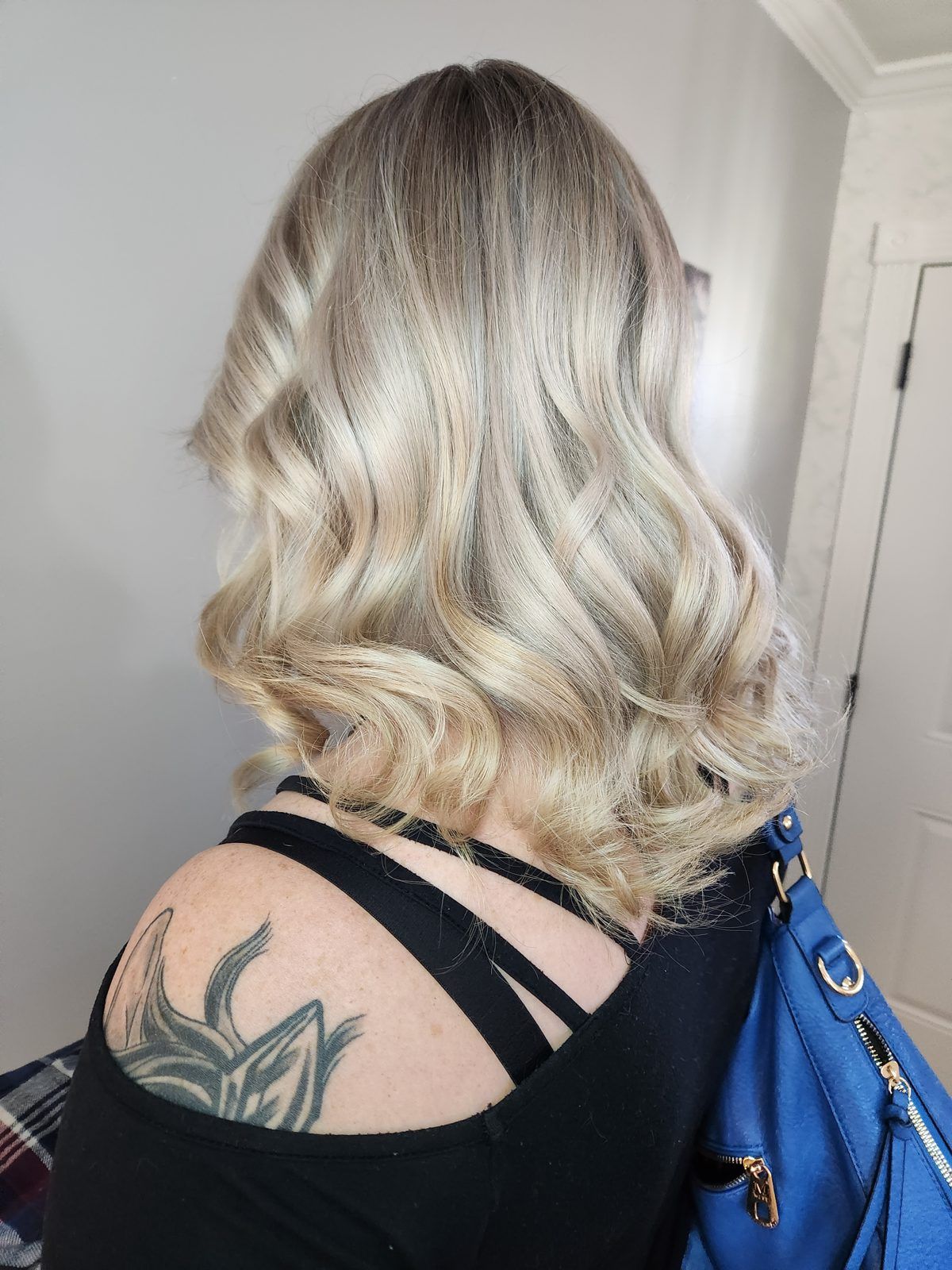 Cool blonde balayage from shadow roots to curled blonde ends, side view.
