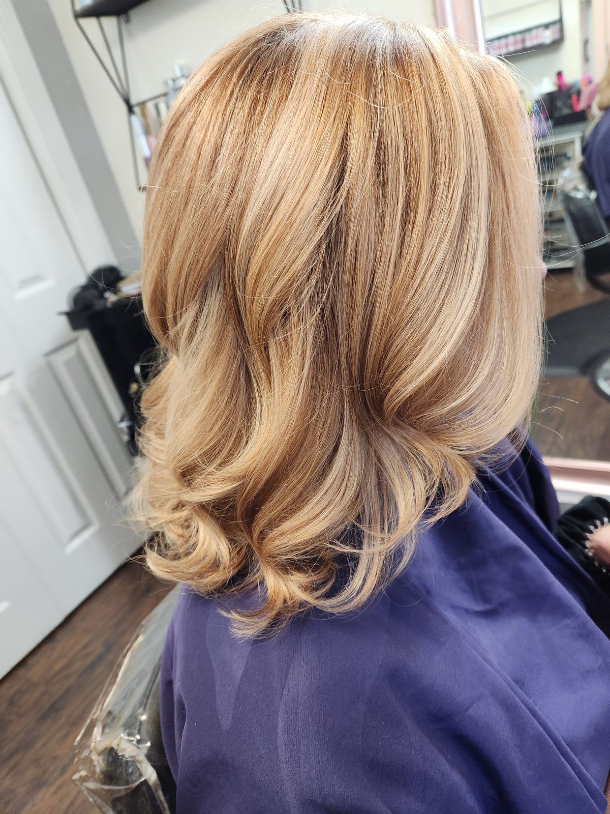 Warm golden-blonde bob with bouncy curled ends, shown from the side.