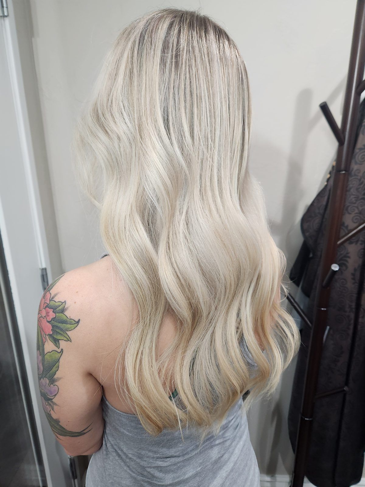 Long icy-blonde balayage in soft waves, shown from the side.