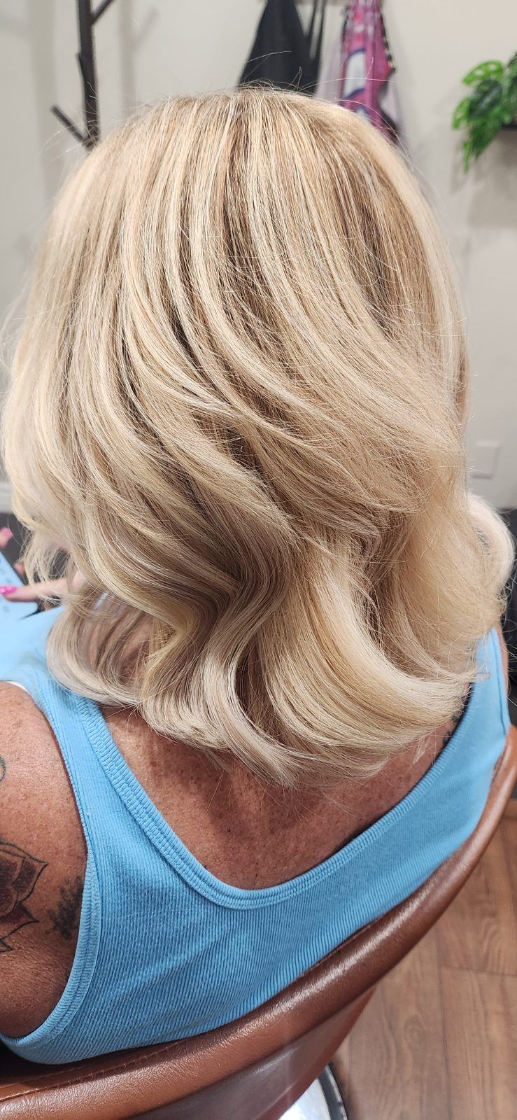 Soft golden-blonde layered blowout with flipped ends, shown from behind.